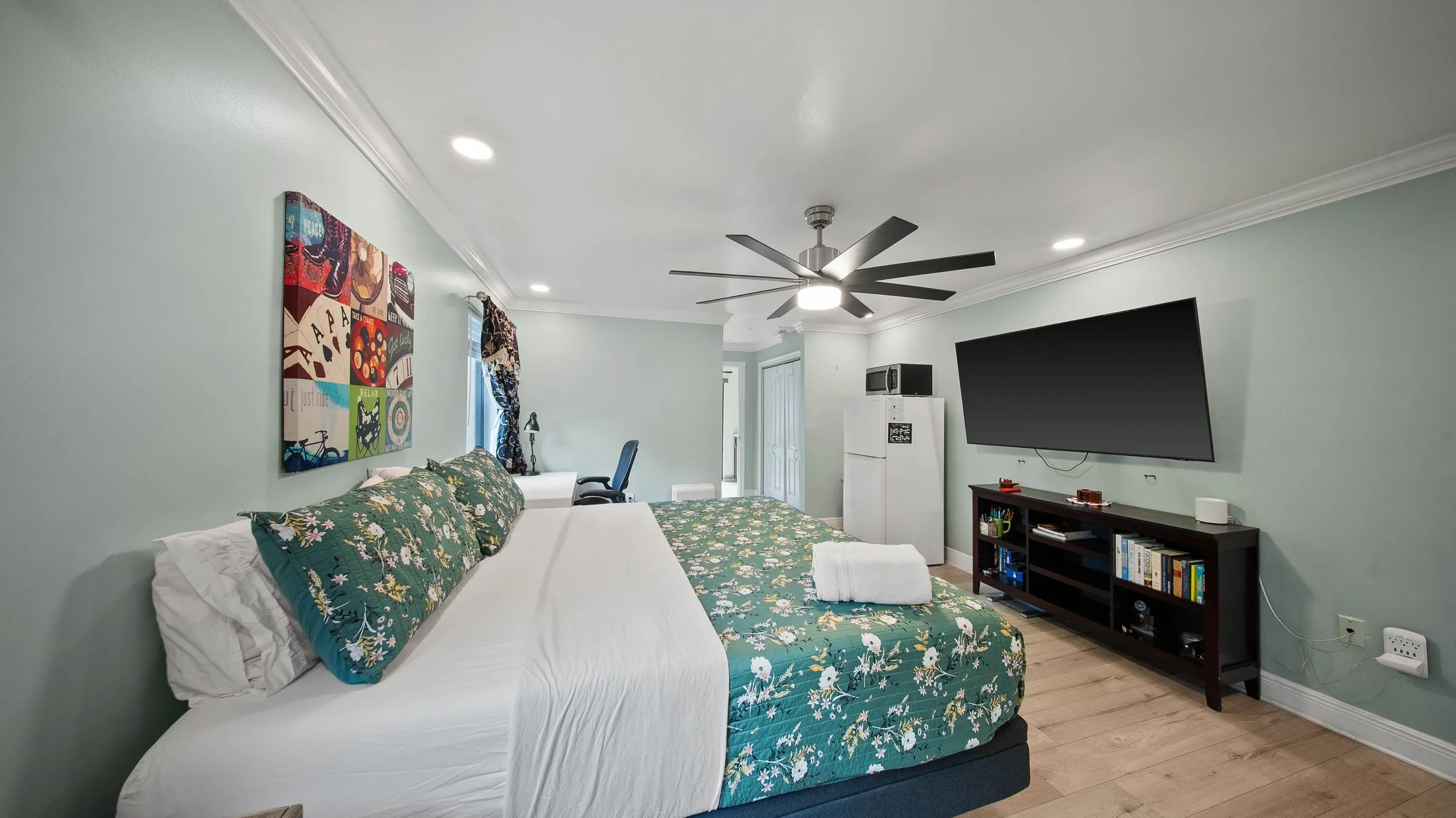 King bed with green floral bedding and ceiling fan in the Master Suite